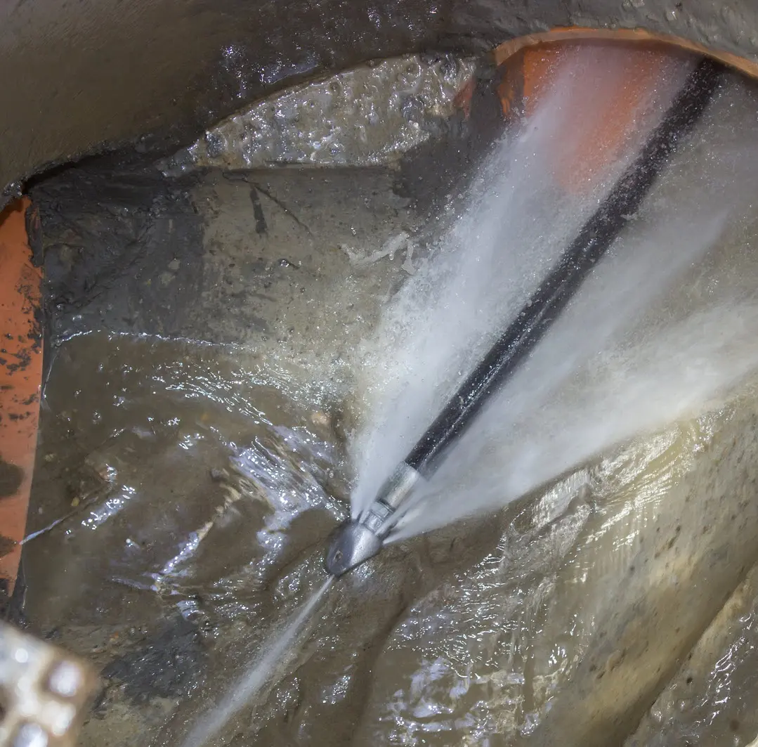Water jets spraying from a nozzle inside a pipe.